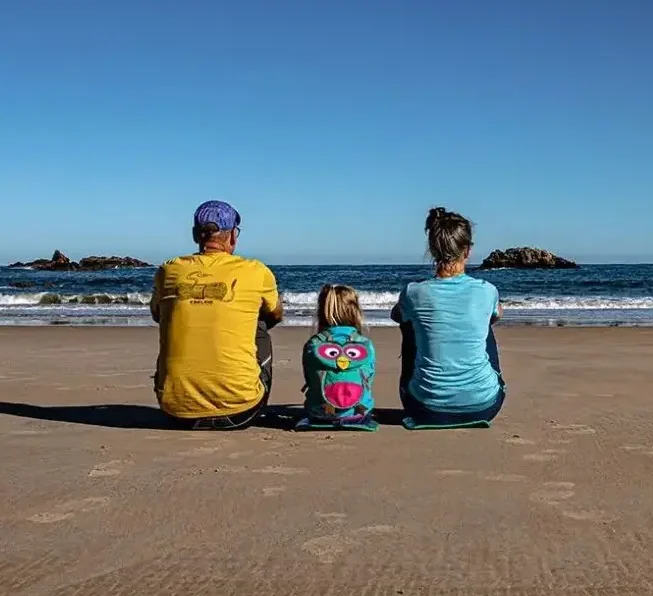 Familie sitzt am Strand, Blick aufs Meer